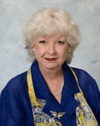 Elderly woman with short white hair smiling.