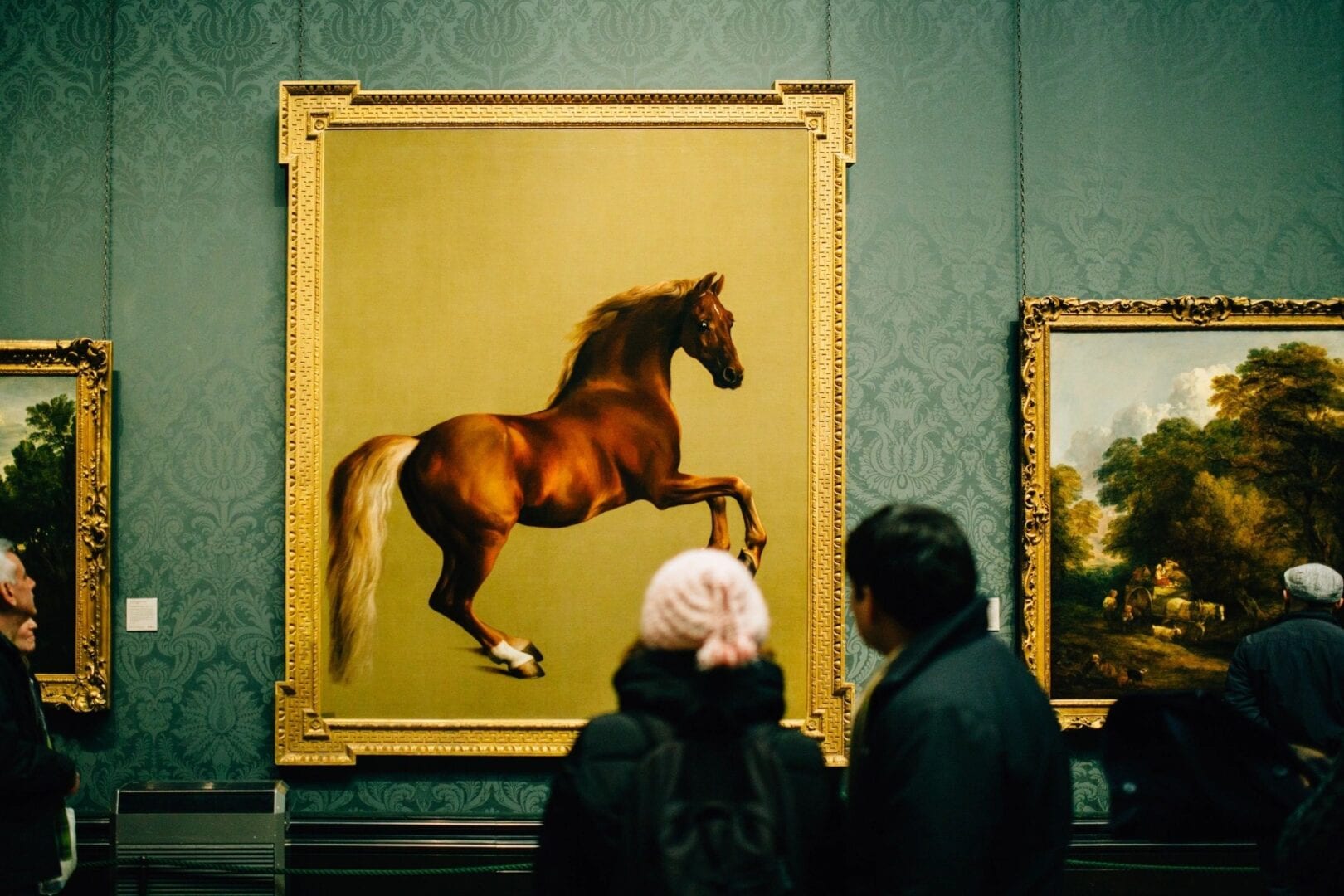 People admire a realistic horse painting in a gallery.
